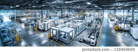 Robotic arms move along assembly lines in a factory. The production area is busy with machinery and equipment. Automation is central to the workflow in this industrial space 138469699