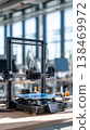 In a workshop filled with natural light, a 3D printer works on engineering prototypes. Tables display tools and materials used for various projects in technology and design 138469972