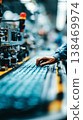 A worker checks finished products moving along a conveyor belt as part of the quality control process in a factory. The focus is on ensuring precision and detail in the work 138469974