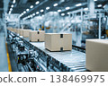 Cardboard packages flow efficiently on a modern roller conveyor belt within a large, brightly lit automated packaging facility 138469975