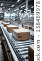 Sealed products travel along a conveyor belt in a factory. Workers manage the packaging process. The factory is busy with operations throughout the day 138469978