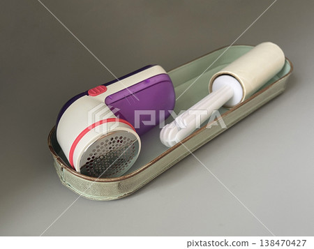 Lint remover and roller sit on a metal tray on a table in a room during the day Lint remover and roller sit on a metal tray on a table in a room during the day 138470427