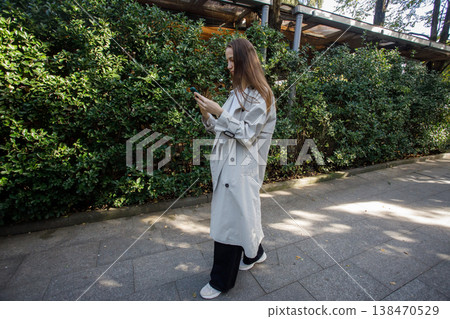 Cute woman with smartphone walking on city street 138470529