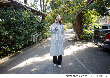 Cute woman talking on smartphone and walking in park outdoors 138470537