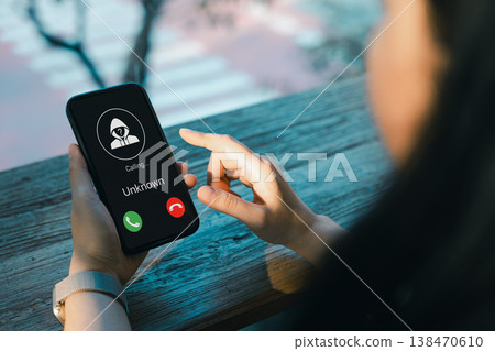 Cybersecurity and scam awareness concept. Woman receiving unknown caller on smartphone screen, highlighting phone fraud, spam risk, identity theft, and the importance of digital privacy protection. Cybersecurity and scam awareness concept. Woman receiving unknown caller on smartphone screen, highlighting phone fraud, spam risk, identity theft, and the importance of digital privacy protection. 138470610