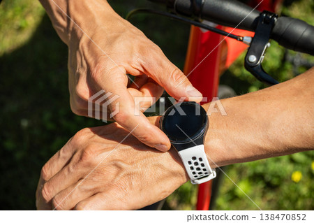 Man checking smartwatch on bicycle handlebar close up Man checking smartwatch on bicycle handlebar close up 138470852