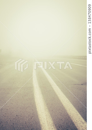 Foggy empty highway. Bad weather on the road. Road on foggy day in perspective with copy space. Driving conditions concept. Caution and danger on the road. Road marking lines on ghostly route. Foggy empty highway. Bad weather on the road. Road on foggy day in perspective with copy space. Driving conditions concept. Caution and danger on the road. Road marking lines on ghostly route. 138470909