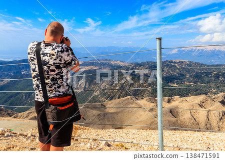 Travel photographer man with professional camera taking photos of  on a top of Tahtali mountain near Kemer, Antalya Province in Turkey 138471591