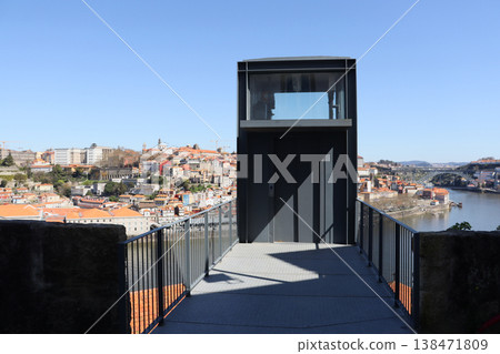 Modern elevator viewpoint in Porto overlooking Douro river and city rooftops. Urban architecture with metal structure and panoramic view. Travel and tourism concept with scenic city perspective. Modern elevator viewpoint in Porto overlooking Douro river and city rooftops. Urban architecture with metal structure and panoramic view. Travel and tourism concept with scenic city perspective. 138471809