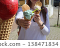 Woman holding ice cream cone with colorful scoops and waffle biscuit outdoors. Sweet dessert for summer enjoyment, street food, casual lifestyle, travel moments and warm weather refreshment. 138471834