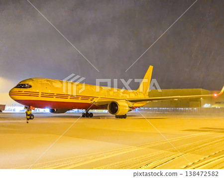 DHL cargo plane on a snowy airport runway at night. Global logistics and air freight transportation in winter weather. 138472582