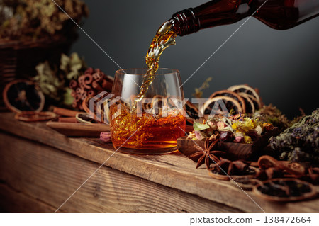 Herbal liquor is poured from a vintage bottle into a glass. 138472664