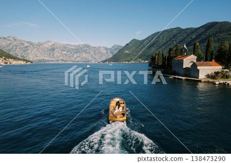 Small Boat Gliding Across Blue Waters Towards Mountainframed Island Chapel Small Boat Gliding Across Blue Waters Towards Mountainframed Island Chapel 138473290