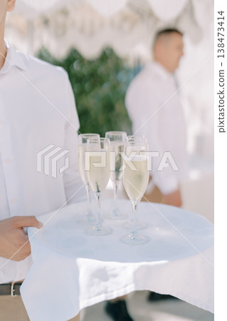 Professional Caterer Presenting Drinks Beneath Sunlit Tent Canopy Professional Caterer Presenting Drinks Beneath Sunlit Tent Canopy 138473414