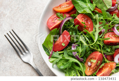 Fresh vegan salad with arugula, tomatoes, and red onion Fresh vegan salad with arugula, tomatoes, and red onion 138473431