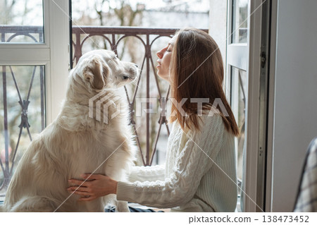 Woman bonding with golden retriever dog on balcony Woman bonding with golden retriever dog on balcony 138473452