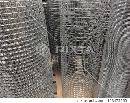 Woven metal cylinders stand tall in a warehouse showcasing their shiny texture Woven metal cylinders stand tall in a warehouse showcasing their shiny texture 138473563