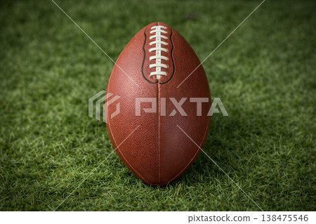 Classic brown football resting on green turf Classic brown football resting on green turf 138475546