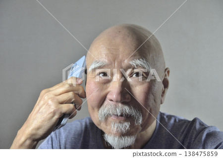 一位留著鬍子的老人拿著一支智慧型手機 138475859