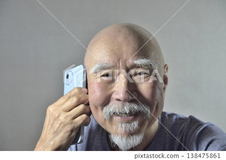 一位留著鬍子的老人拿著一支智慧型手機 一位留著鬍子的老人拿著一支智慧型手機 138475861