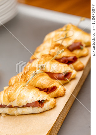 Row of ham and cheese croissants on wooden board Row of ham and cheese croissants on wooden board 138476077