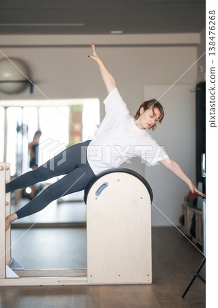 Woman exercising on pilates ladder barrel practicing side bend Woman exercising on pilates ladder barrel practicing side bend 138476268
