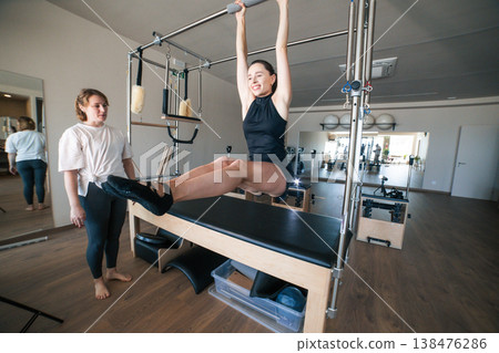 Woman exercising pilates cadillac with personal trainer Woman exercising pilates cadillac with personal trainer 138476286