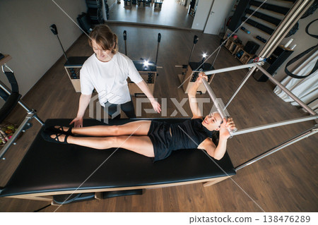 Woman exercising pilates with personal trainer guidance Woman exercising pilates with personal trainer guidance 138476289