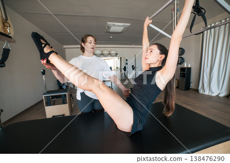Woman exercising pilates with instructor for body control 138476290