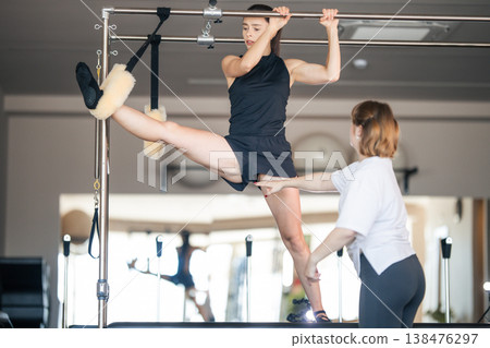 Woman stretching leg on pilates cadillac during fitness class 138476297