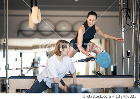 Pilates instructor guiding woman with reformer exercise Pilates instructor guiding woman with reformer exercise 138476325