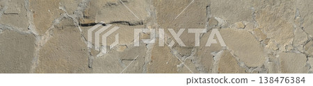 Rough gray natural stone wall with irregular flagstone cladding and weathered beige surface texture. Rough gray natural stone wall with irregular flagstone cladding and weathered beige surface texture. 138476384