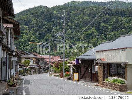 A quiet Japanese street surrounded by lush green mountains 138476655