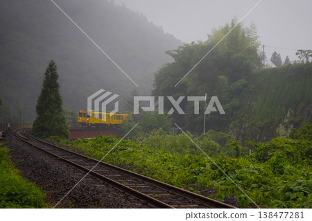 A yellow local train making its way through the morning mist. 138477281