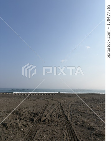 Tracks leading to the sandy beach; a deserted sea and a vast sky. 138477865