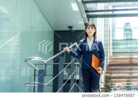 一位身穿西裝的年輕女子走進辦公大樓入口。 138478087
