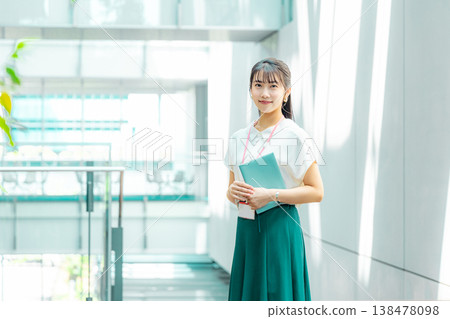A young woman walking down the hallway with her notebook in her hand. A young woman walking down the hallway with her notebook in her hand. 138478098