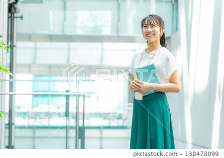 A young woman walking down the hallway with her notebook in her hand. A young woman walking down the hallway with her notebook in her hand. 138478099