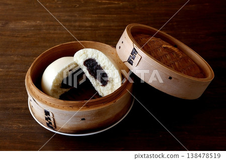 桌子背景中蒸籠裡裝著芝麻餡包子。 138478519