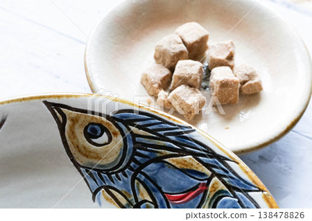 Okinawan crafts and food: Simple brown sugar served in Yachimun pottery. Okinawan crafts and food: Simple brown sugar served in Yachimun pottery. 138478826