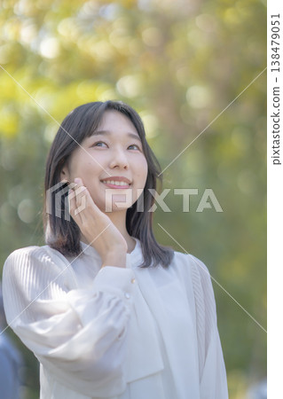 A young woman shields her eyes from the bright sunlight; natural light; refreshing; beauty image. 138479051