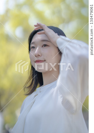 A young woman shields her eyes from the bright sunlight; natural light; refreshing; beauty image. 138479061