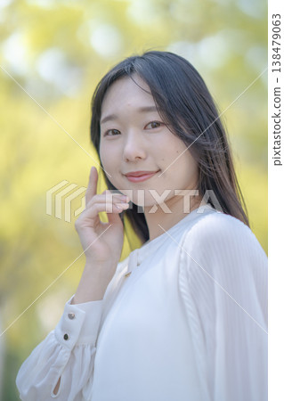 A young woman shields her eyes from the bright sunlight; natural light; refreshing; beauty image. 138479063