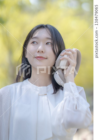 A young woman using wireless headphones in nature, outdoors, refreshing. A young woman using wireless headphones in nature, outdoors, refreshing. 138479065