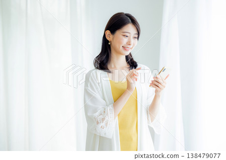一個年輕女子在家裡看智能手機 138479077
