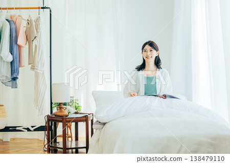 A woman reading a magazine in her bedroom 138479110