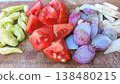 A vibrant display of fresh, chopped vegetables including red tomatoes, purple shallots, white garlic, and green chilies, neatly arranged on a rustic wooden cutting board, ready for cooking a healthy 138480215