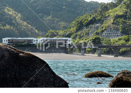 在晴朗的藍天下，JR九州日南線紀波40號列車駛過宮崎縣日南市的山王海灘。 138480685