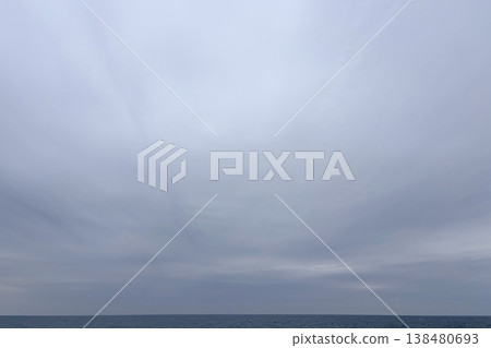 A calm sea and horizon stretch out beneath the cloudy sky. A calm sea and horizon stretch out beneath the cloudy sky. 138480693