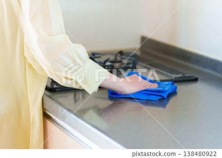 A woman's hands cleaning a gas stove 138480922